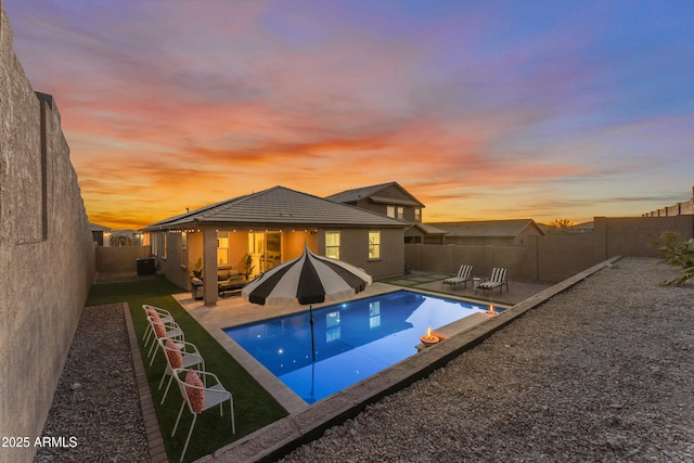 pool at dusk with a patio area