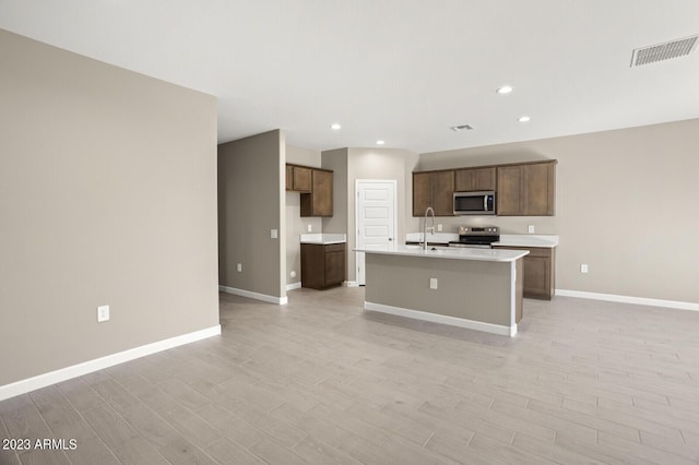 kitchen featuring light hardwood / wood-style floors, sink, an island with sink, and appliances with stainless steel finishes