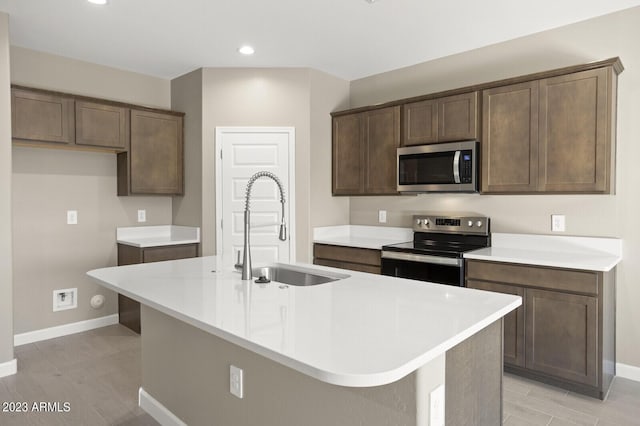 kitchen featuring appliances with stainless steel finishes, dark brown cabinetry, a kitchen island with sink, and sink