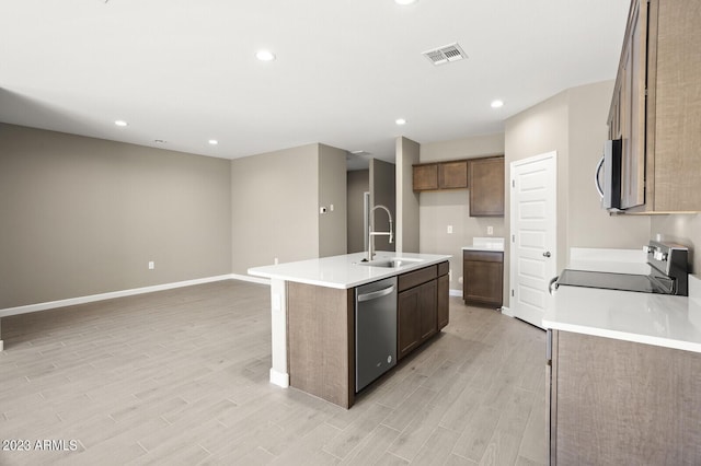 kitchen featuring a kitchen island with sink, sink, stainless steel appliances, and light hardwood / wood-style floors