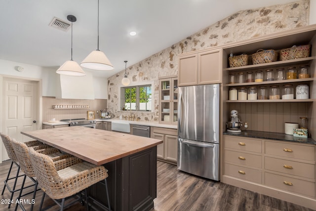 kitchen with a kitchen island, a kitchen breakfast bar, decorative light fixtures, wood counters, and appliances with stainless steel finishes