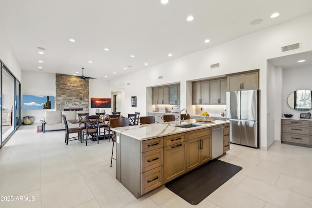 kitchen featuring visible vents, an island with sink, ceiling fan, a sink, and appliances with stainless steel finishes