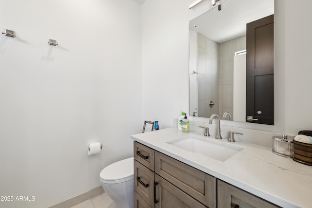 bathroom featuring tile patterned flooring, vanity, toilet, baseboards, and a tile shower