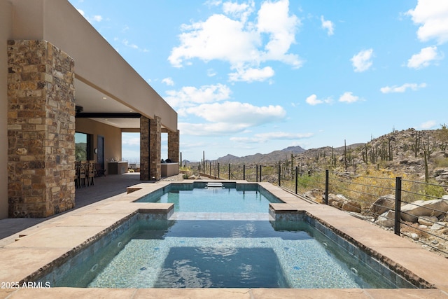 view of swimming pool with fence, outdoor dry bar, a patio area, a mountain view, and a pool with connected hot tub