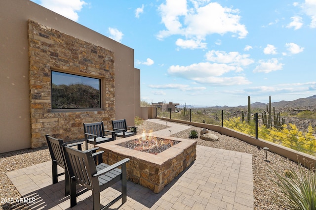 view of patio / terrace featuring fence, a fire pit, and a mountain view