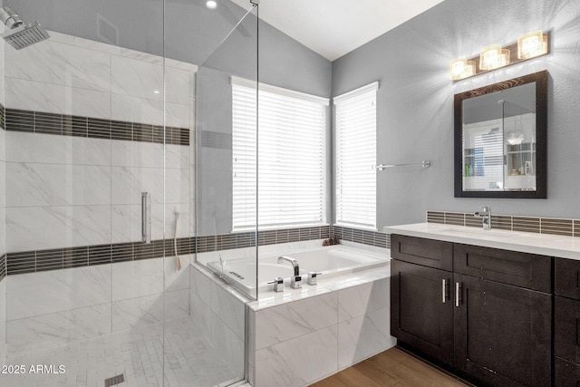 bathroom featuring wood finished floors, a stall shower, vanity, and a bath