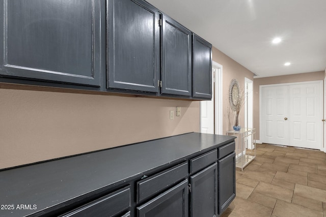 kitchen featuring dark countertops, baseboards, and recessed lighting