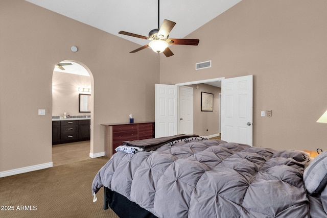 bedroom with arched walkways, high vaulted ceiling, light colored carpet, visible vents, and baseboards