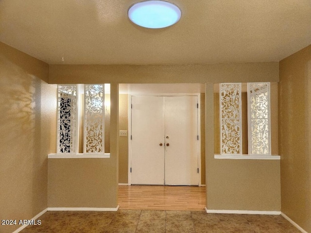 entryway with a textured ceiling and light tile patterned flooring