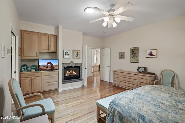 bedroom with a multi sided fireplace, ceiling fan, and light wood-type flooring