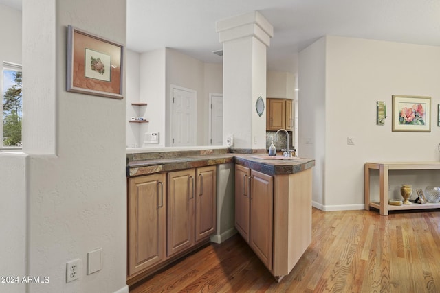 kitchen featuring decorative columns, wood-type flooring, sink, and kitchen peninsula