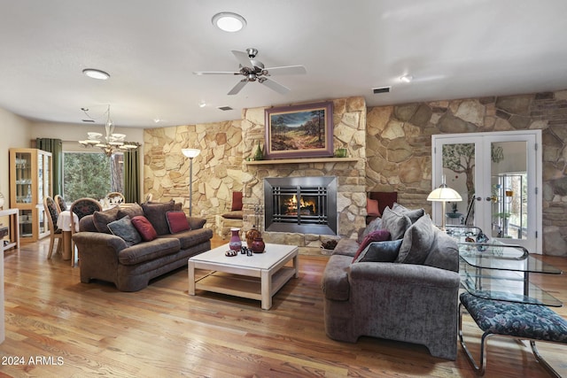 living room featuring hardwood / wood-style flooring, a fireplace, an inviting chandelier, and french doors