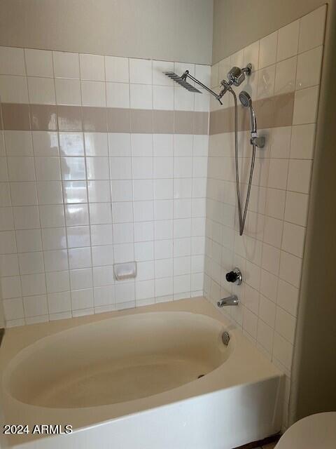 bathroom with toilet and tiled shower / bath combo