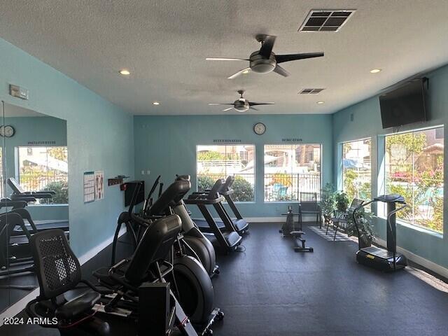 exercise room with ceiling fan and a textured ceiling