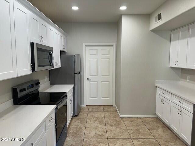 kitchen with appliances with stainless steel finishes, white cabinetry, and light tile patterned floors