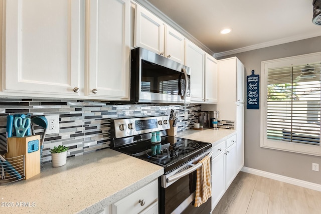 kitchen with baseboards, white cabinets, appliances with stainless steel finishes, tasteful backsplash, and crown molding