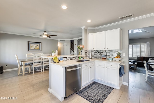 kitchen with visible vents, backsplash, white cabinetry, a sink, and dishwasher