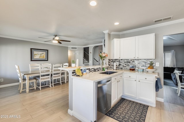 kitchen featuring visible vents, decorative backsplash, a peninsula, stainless steel dishwasher, and a sink