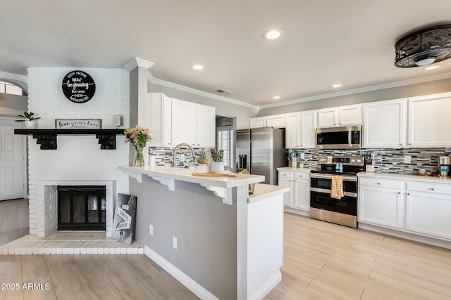 kitchen with tasteful backsplash, white cabinets, a peninsula, stainless steel appliances, and light countertops