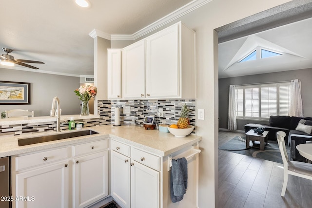 kitchen featuring crown molding, tasteful backsplash, white cabinetry, a sink, and wood finished floors