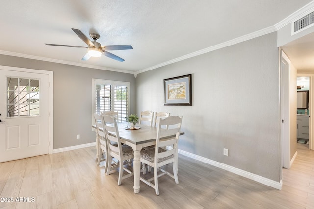 dining room with light wood-style floors, visible vents, crown molding, and baseboards