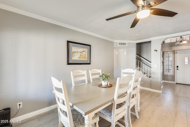 dining room with crown molding, visible vents, light wood-style flooring, baseboards, and stairs