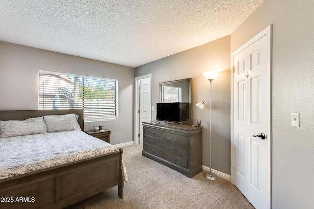 bedroom with light carpet, baseboards, and a textured ceiling