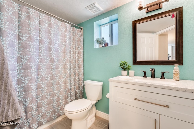 bathroom featuring visible vents, a textured wall, toilet, wood finished floors, and vanity