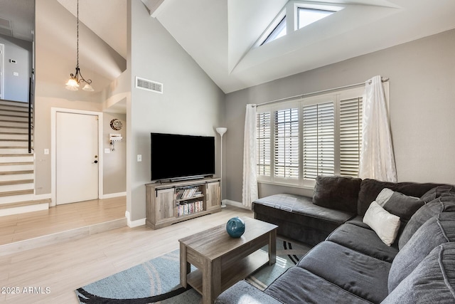 living room with visible vents, stairway, an inviting chandelier, light wood-style floors, and high vaulted ceiling