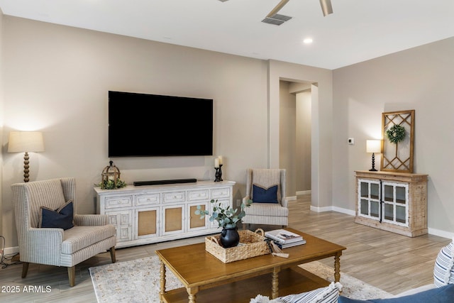 living room featuring baseboards, a ceiling fan, wood finished floors, and visible vents