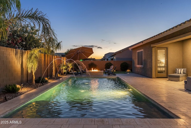 pool at dusk featuring a fenced in pool, a fenced backyard, a patio area, and an outdoor fire pit