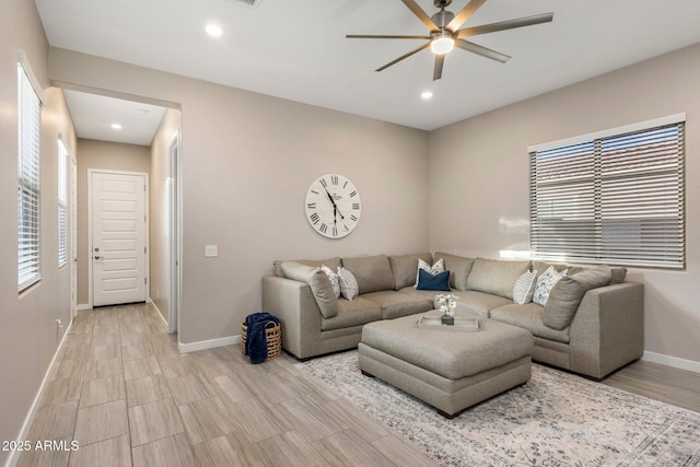 living area with baseboards, a ceiling fan, recessed lighting, and light wood-type flooring