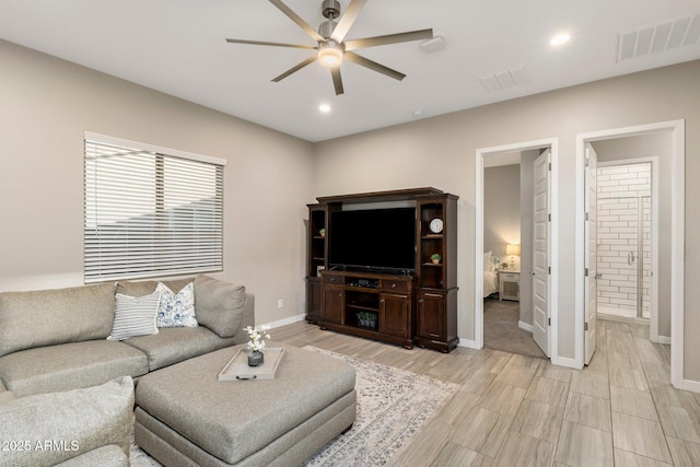 living area featuring visible vents, baseboards, and ceiling fan