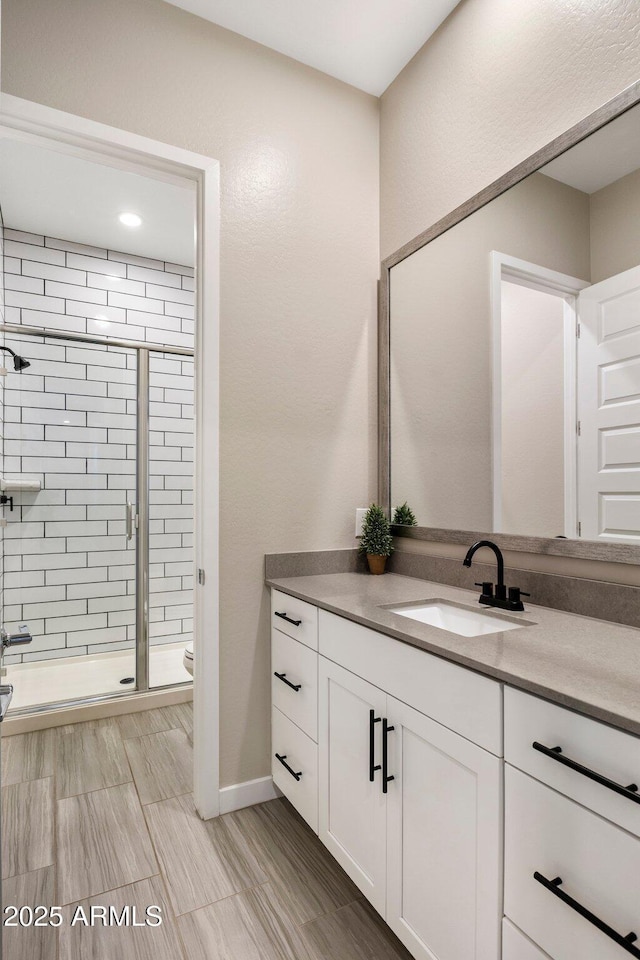 bathroom with vanity, baseboards, a stall shower, and toilet