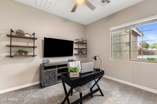 office space featuring a ceiling fan, baseboards, visible vents, and light colored carpet