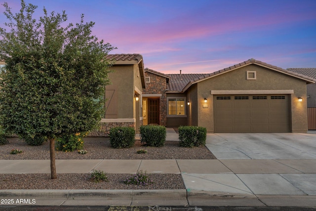 view of front of house featuring an attached garage, stucco siding, stone siding, and a tile roof