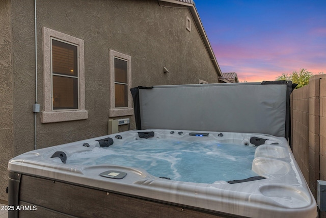 exterior space featuring a jacuzzi and stucco siding