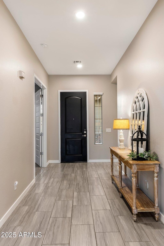 foyer with baseboards, wood finish floors, and visible vents