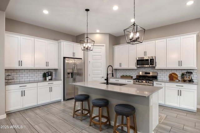 kitchen with a sink, appliances with stainless steel finishes, backsplash, and a notable chandelier