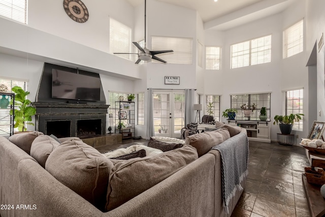 living room featuring ceiling fan, a towering ceiling, a fireplace, and a wealth of natural light