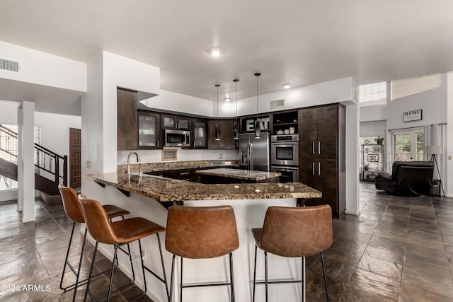 kitchen with kitchen peninsula, a breakfast bar, dark brown cabinets, stainless steel appliances, and decorative light fixtures