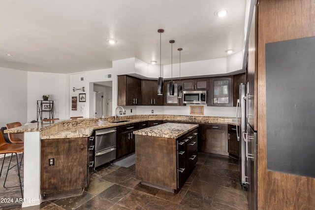 kitchen with dark brown cabinetry, sink, pendant lighting, a breakfast bar area, and a kitchen island