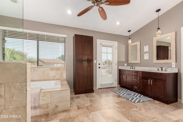 bathroom featuring ceiling fan, vanity, lofted ceiling, and tiled bath