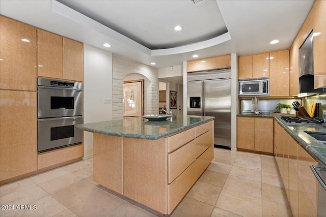 6516 E Maverick Rd, Paradise Valley, AZ 85253 - kitchen with a tray ceiling, dark stone countertops, decorative backsplash, a kitchen island, and built in appliances