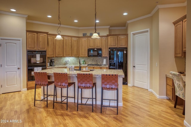 kitchen featuring an island with sink, black appliances, and a breakfast bar