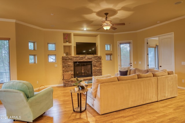 living area with ornamental molding, baseboards, a fireplace, and light wood finished floors