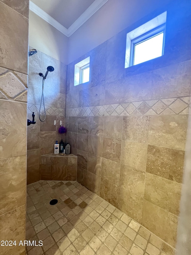 bathroom featuring ornamental molding, tiled shower, and a wealth of natural light