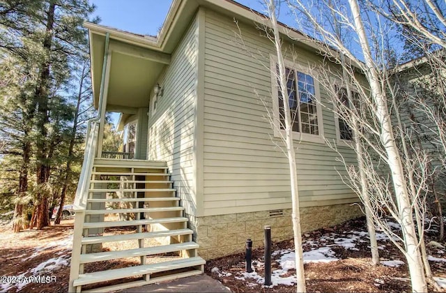 view of snowy exterior with crawl space and stairs