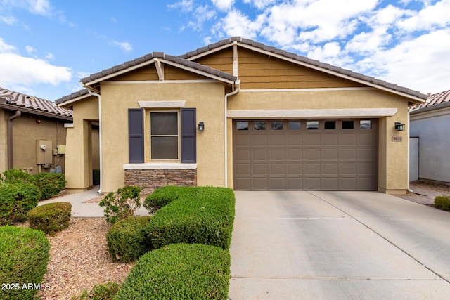 view of front of property featuring stucco siding, driveway, a tile roof, stone siding, and an attached garage