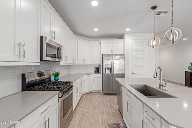 kitchen with light countertops, decorative backsplash, stainless steel appliances, white cabinetry, and a sink